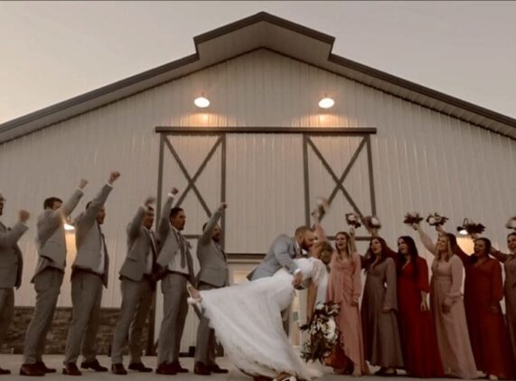 Bridal Party outside of Wedding Barn. Couple in a deep dip kissing.