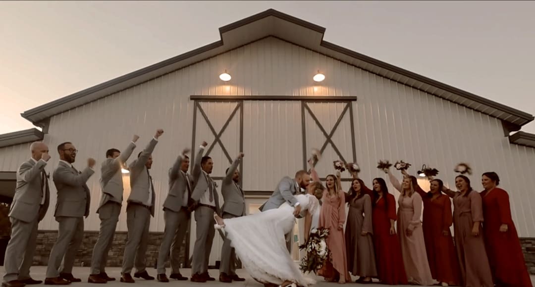 Bridal Party outside of Wedding Barn. Couple in a deep dip kissing.
