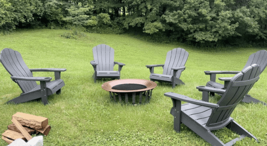 This is an image of a brass firepit and 5 Adirondack chairs for guests at the Ross Mansion at The Barns at Marengo Cave.