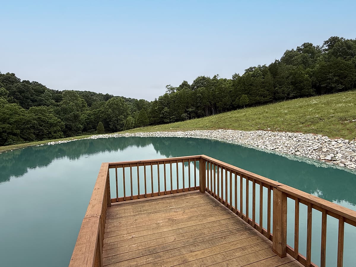 The small lake with wooden walkway deck extending into the water at The Barns at Marengo Cave venue.