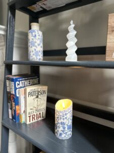 Beautifully appointed shelves in the living room at the Ross Mansion at The Barns at Marengo Cave. Image shows lit, battery operated candle, books and art pieces.